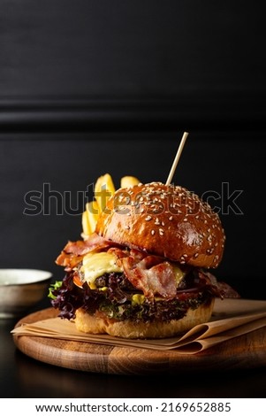 Big American burger with bacon meat cheese and salad black copy space