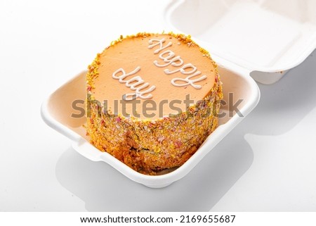 Bento cake with inscription, Happy day, in plastic box-packaging. Carrot cake isolated on white background