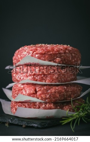 Raw ground beef burger patties separated by baking paper on a black background Royalty-Free Stock Photo #2169664017