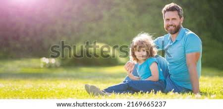 Banner of father and son in summer park outdoor. happy family portrait of father and son boy relax in summer park green grass, family love