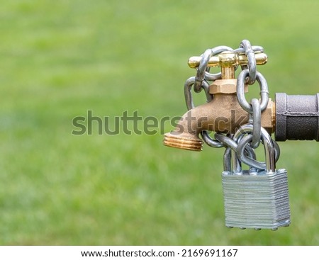 Outdoor water faucet with lock and chain. Water restriction, supply and shortage concept Royalty-Free Stock Photo #2169691167