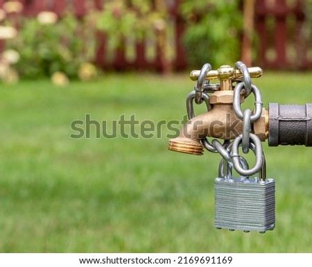 Outdoor water faucet with lock and chain. Water restriction, supply and shortage concept Royalty-Free Stock Photo #2169691169