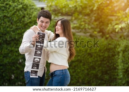 happy pregnant woman with her husband watching ultrasound photo of baby. married couple.