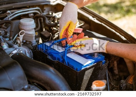 A man removes a battery from under the hood of a car. Battery replacement and repair. Royalty-Free Stock Photo #2169732597