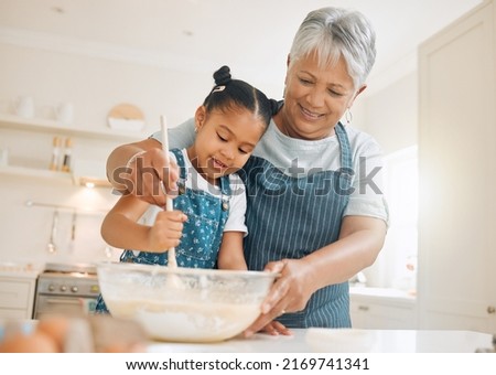 You have to stir it like you mean it. Shot of a little girl baking with her grandmother at home. Royalty-Free Stock Photo #2169741341