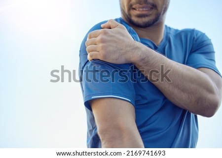 Did I dislocate my shoulder. Cropped shot of an unrecognisable man standing alone and suffering from shoulder pain during his outdoor workout. Royalty-Free Stock Photo #2169741693