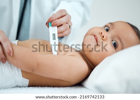 Lets start by taking your temperature. Shot of a paediatrician taking a babys temperature with a thermometer in a clinic. Royalty-Free Stock Photo #2169742133