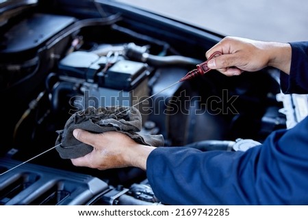 Checking your oil. High angle shot of an unrecognizable male mechanic working on the engine of a car during a service. Royalty-Free Stock Photo #2169742285
