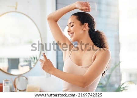 Staying fresh all day. Shot of a young woman applying deodorant to her underarm at home. Royalty-Free Stock Photo #2169742325