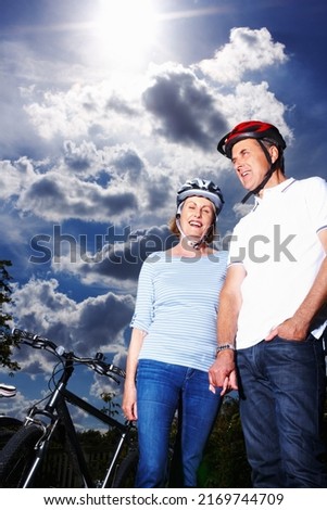 Romantic senior couple standing by bicycle against cloudy sky. Low section of romantic senior couple standing by bicycle against cloudy sky.
