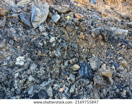 The surface of the earth wall with an irregular pattern, the exposed coal on the surface of the earth wall is scattered,