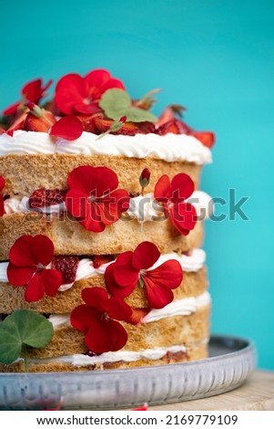 beautiful biscuit cake with strawberries decorated with natural geranium flowers
