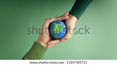 World Earth Day Concept. Green Energy, ESG, Renewable and Sustainable Resources. Environmental Care. Hands of People  Embracing a Handmade Globe. Protecting Planet Together. Top View Royalty-Free Stock Photo #2169784725
