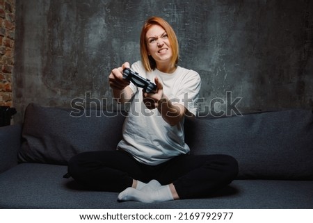 A young woman who holds a joystick in her hands and plays a game console