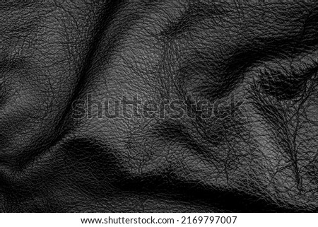 Bright natural real black leather with ruckled waves background. Leather texture abstract close-up.