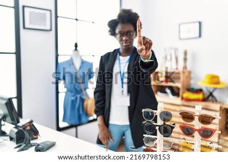 African young woman working as manager at retail boutique pointing with finger up and angry expression, showing no gesture 