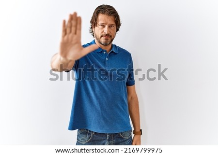 Handsome middle age man standing together over isolated background doing stop sing with palm of the hand. warning expression with negative and serious gesture on the face. 