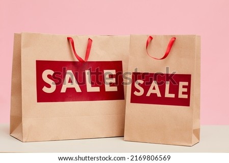 Close-up of shopping paper bags with Sale lettering in red color placed on counter of store