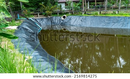 Plastic covering at pond background. Installation black plastic film cover pool for agriculture 