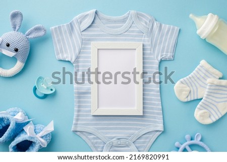 Baby accessories concept. Top view photo of photo frame blue bodysuit socks knitted bunny rattle toy bottle teether booties and soother on isolated pastel blue background with blank space
