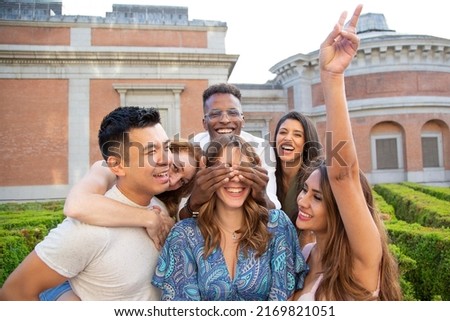 Group of multicultural friends covering the eyes of a friend to surprise her