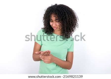 Young beautiful girl with afro hairstyle wearing green t-shirt over white background Suffering pain on hands and fingers, arthritis inflammation