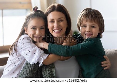 Headshot portrait of happy young Caucasian mother hug cuddle with cute small excited children at home. Loving caring two little kids embrace mom show affection and support. Family concept. Royalty-Free Stock Photo #2169827665
