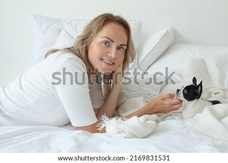 Woman sitting with her chihuahua dog on sofa in room