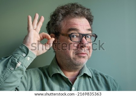 Mature man with glasses showing ok sign with hand