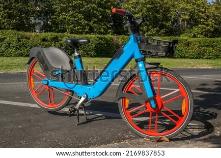 A blue electric bike parked outside a city park. Sustainable and clean mobility. Royalty-Free Stock Photo #2169837853