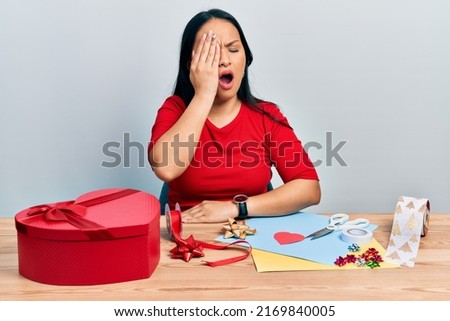 Beautiful hispanic woman with nose piercing doing handcraft creative decoration yawning tired covering half face, eye and mouth with hand. face hurts in pain. 