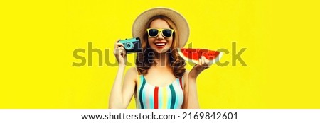 Summer portrait of happy smiling young woman with film camera and slice of fresh watermelon wearing straw hat on yellow background, blank copy space for advertising text