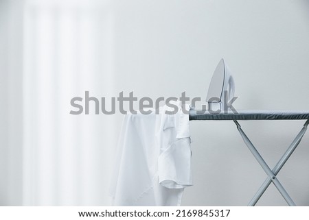 White shirt and iron on ironing board Royalty-Free Stock Photo #2169845317