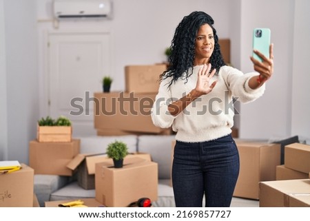 Middle age hispanic woman moving to a new home taking selfie picture looking positive and happy standing and smiling with a confident smile showing teeth 