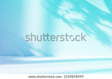 Abstract gradient blue studio background for product presentation. Empty room with shadows of window and flowers and palm leaves . 3d room with copy space. Summer concert. Blurred backdrop. Royalty-Free Stock Photo #2169858499