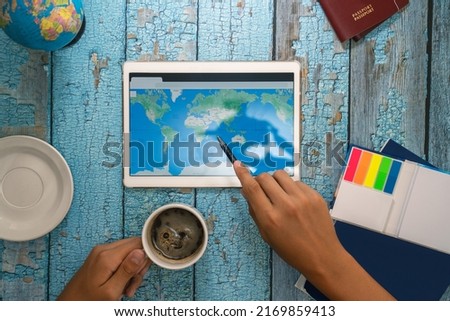 A man's hand holds a pencil that points to a location on a map on a tablet.Vacation planning ahead.Travel concept