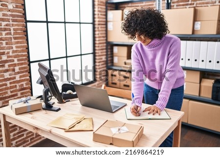 Young middle east woman ecommerce busines worker using laptop writing on document at office