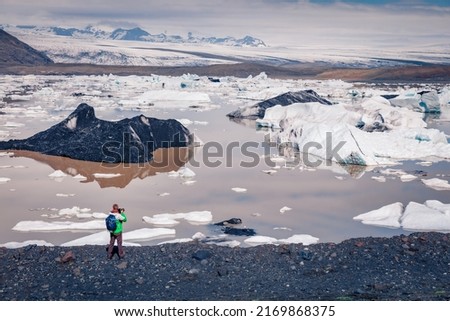 Photographer takes picture of floating ice box on the Fjallsarlon glacial lagoon. Unbelievable morning scene in Vatnajokull National Park, southeast Iceland, Europe. Traveling concept background.

