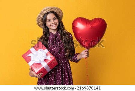 happy teen girl with red heart balloon and present box on yellow background