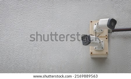 Closeup of white cctv digital security camera installed on cement wall for observation.	Surveillance and safety monitoring concept.