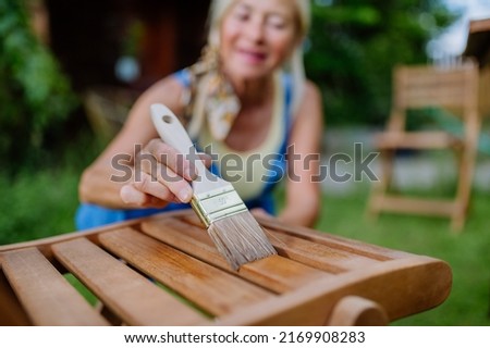 Senior woman cleaning and renovating garden furniture and getting the garden ready for summer Royalty-Free Stock Photo #2169908283