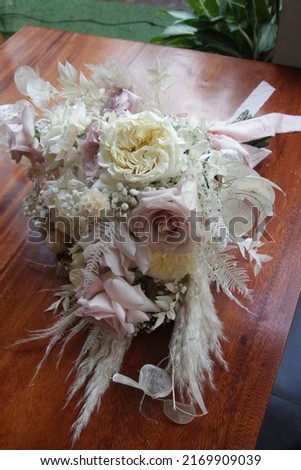a hand bouquet for a wedding consisting of several white, pink flowers, tied with a pink ribbon