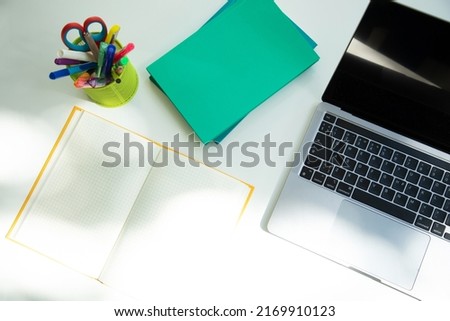 White office table with laptop, notebooks and office supplies in green glass. Flat lay