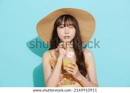 Portrait of young Asian woman in resort fashion on blue background