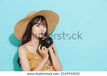 Portrait of young Asian woman in resort fashion on blue background