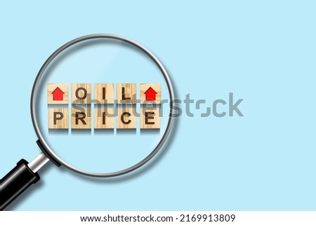 Rise in oil prices. Words on wooden blocks, on a blue background. Magnifying glass.Copy space. World crisis. Business. Economics.