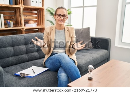 Young woman working at consultation office smiling cheerful with open arms as friendly welcome, positive and confident greetings 