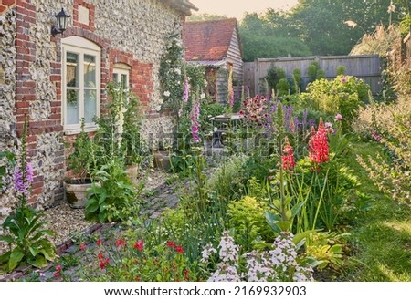 English Country Garden with cottage garden plants in summer and a flint wall Royalty-Free Stock Photo #2169932903