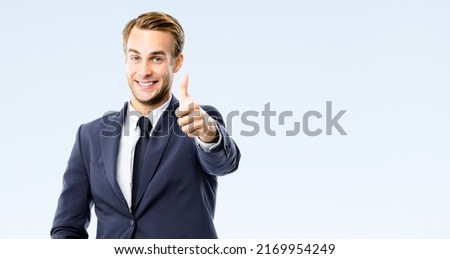 Happy businessman in black suit, white shirt, necktie show thumb finger up, like, agree hand gesture, isolated on grey background. Excited young business man at studio image. Success ad concept. Royalty-Free Stock Photo #2169954249