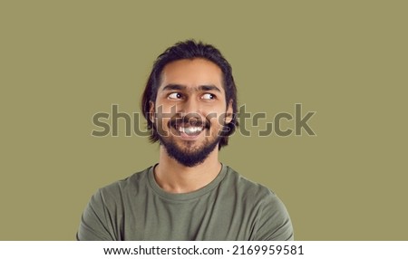 Man feels uncomfortable and looks to side. Head shot bearded mustached South Asian guy experiencing awkward moment. Funny guy likes something, admires someone, casts secret glance sideways and smiles Royalty-Free Stock Photo #2169959581